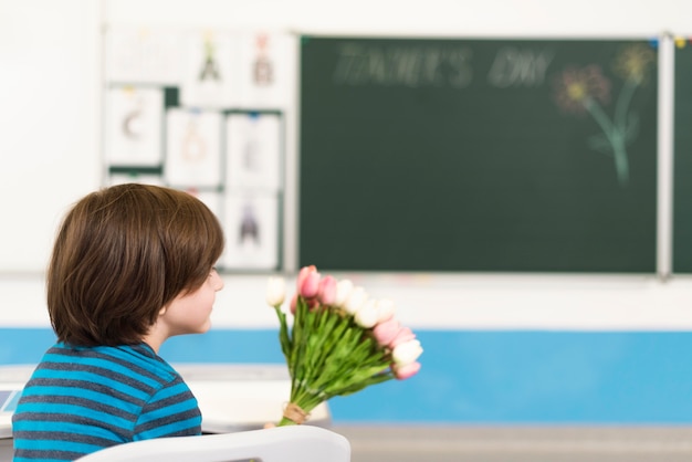 Kid holding a bouquet of flowers for his teacher