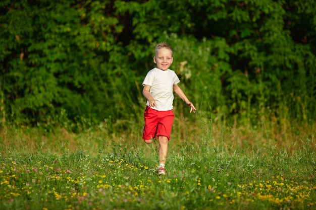 Free photo kid, little boy running on meadow in summer's sunlight