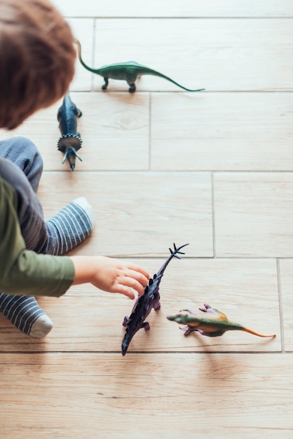 Free photo kid playing with toy dinosaurs