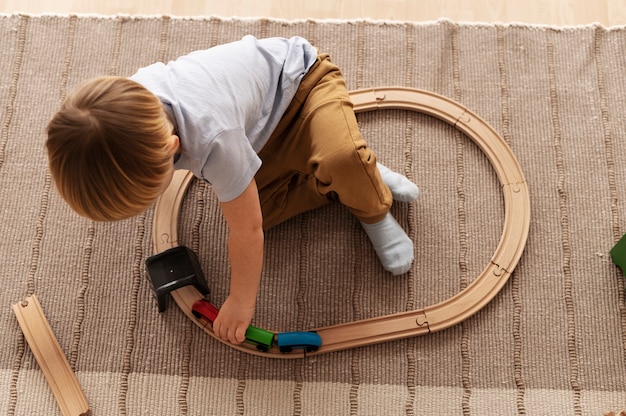 Free photo kid playing with wooden train full shot