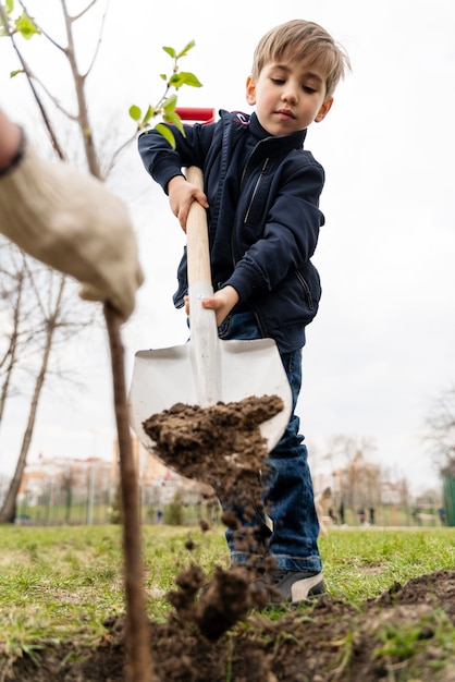 Kid trying to plant a tree outdoors