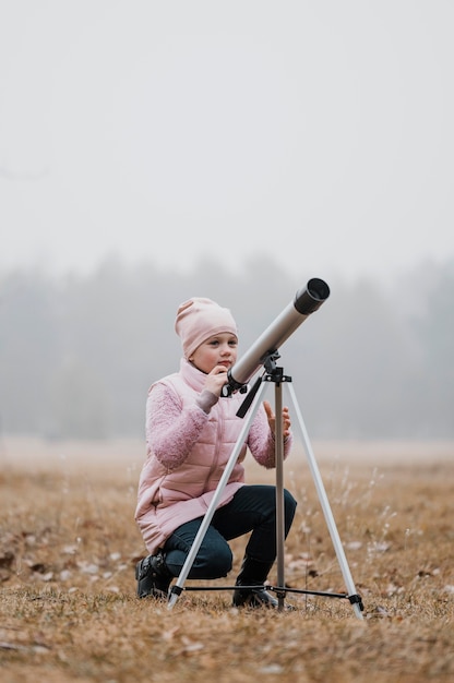 Kid using a telescope outside