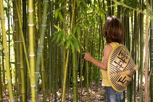 Free photo kid walking through a bamboo forest