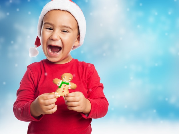 Kid with a christmas hat and a gingerbread