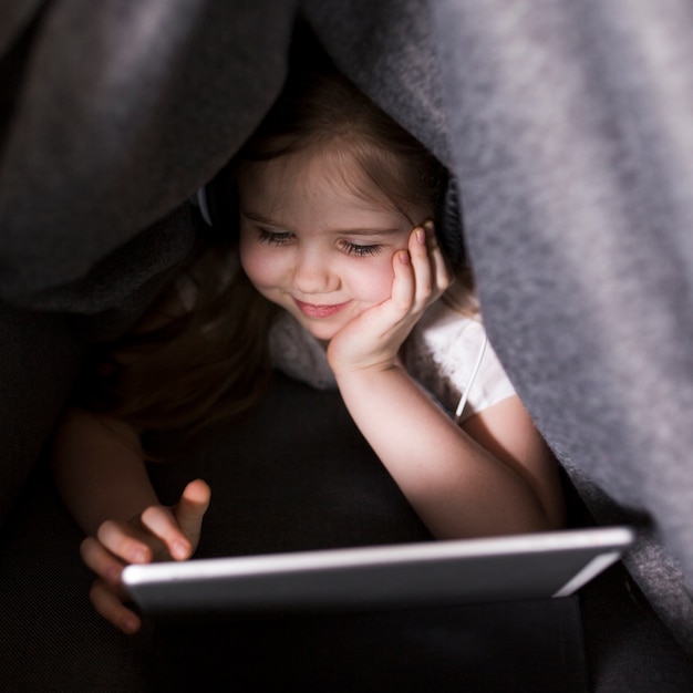 Kid with tablet under blanket