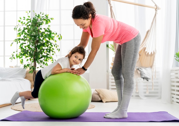 Kid and woman training  with gym ball