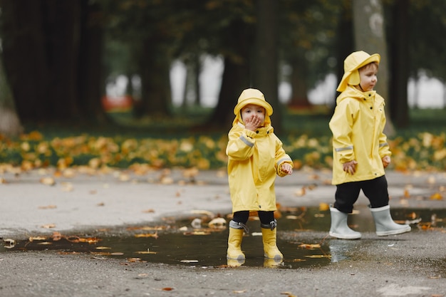 Kids in a autumn park. Children in a yellow raincoats. People having fun outdoors.