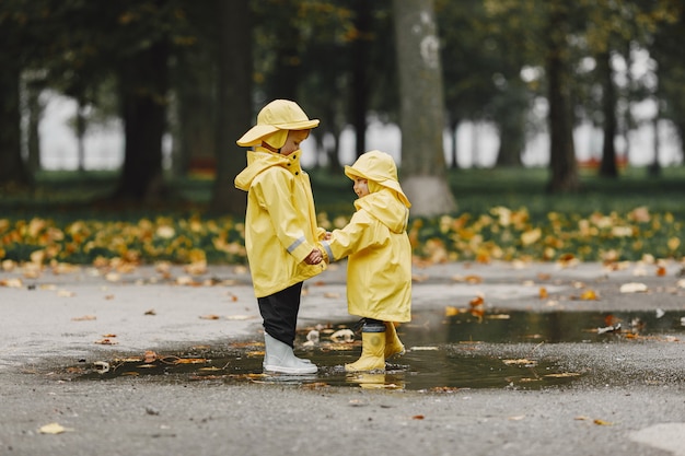 Kids in a autumn park. Children in a yellow raincoats. People having fun outdoors.