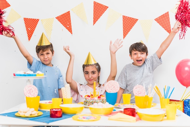 Kids celebrating birthday party at home with variety of food on table