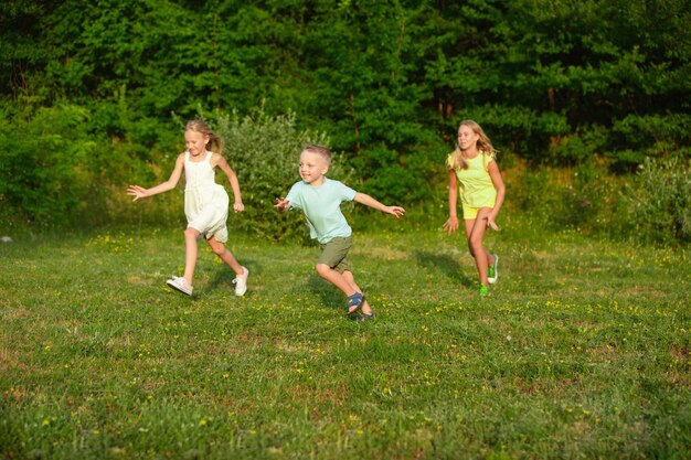 Kids, children running on meadow in summer's sunlight