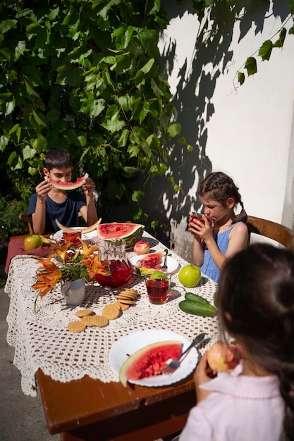 Free Photo kids eating together at a table outdoors