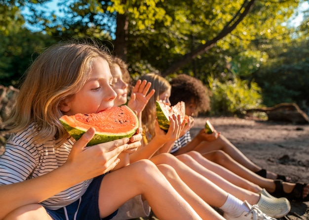 Kids eating watermelon side view