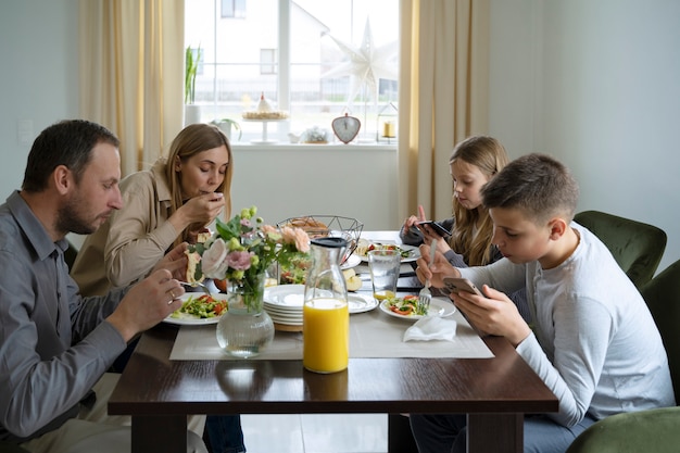 Free Photo kids eating with smartphone side view