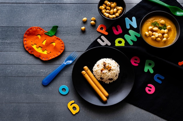 Free photo kids halloween party food with pumpkin risotto and frankfurters, background wallpaper