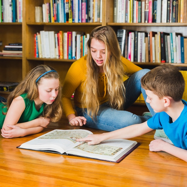 Free photo kids looking at pictures in library book