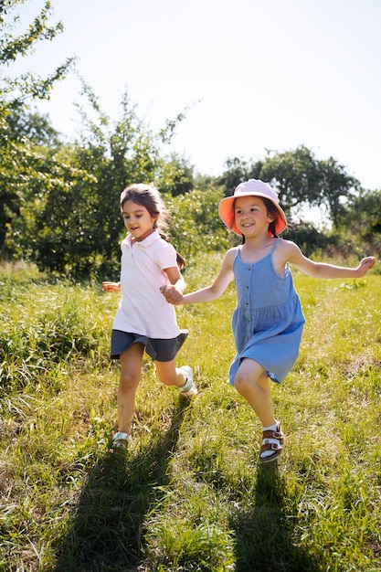 Free photo kids running and playing in grass field outdoors