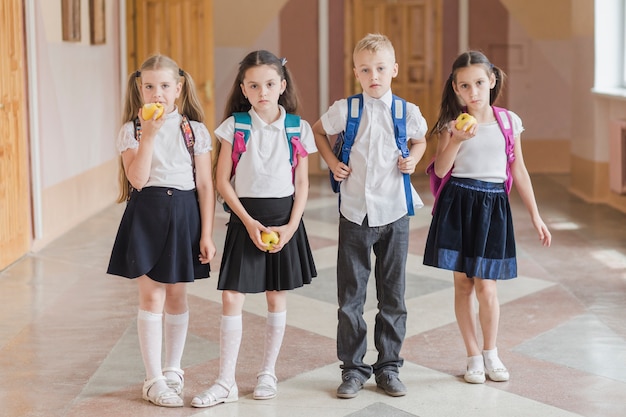 Free photo kids with apples standing in school corridor