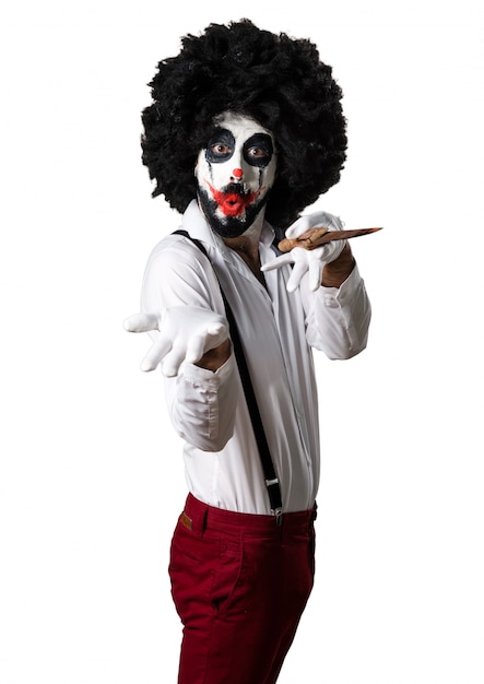 Killer clown with knife presenting something