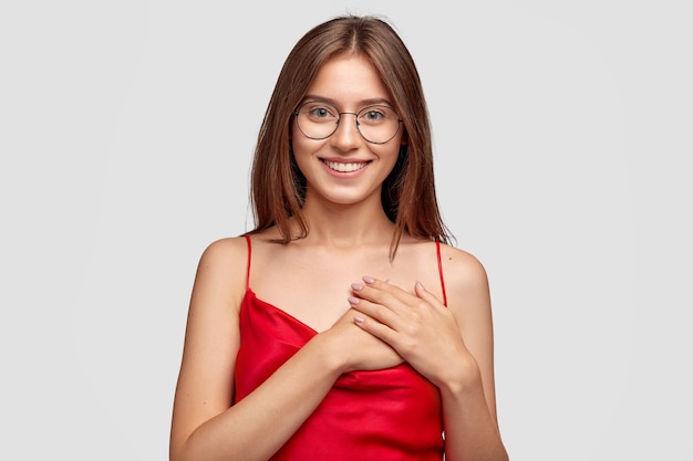 Free photo kind friendly brunette young woman posing against the white wall