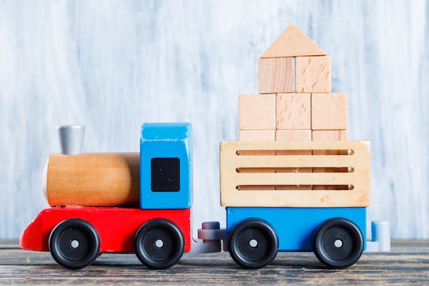 Free photo kindergarten concept with wooden blocks, kid toys on wooden and grungy background side view.