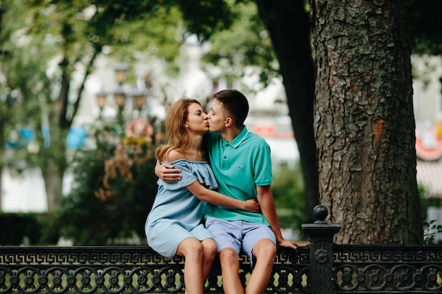 Free photo kissing couple sitting on fence outside