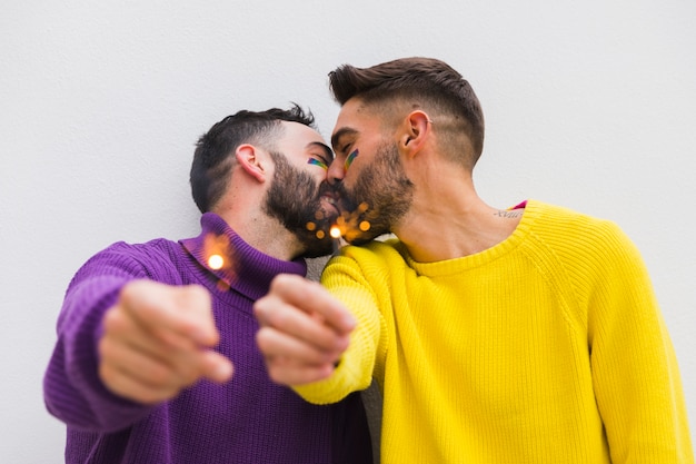 Free photo kissing homosexual pair holding bengal lights