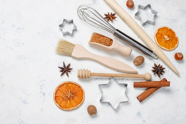 Kitchen baking utensils with spices for cookies and cookie cutters on light surface