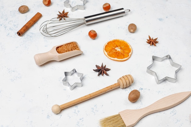 Kitchen baking utensils with spices for cookies and cookie cutters on light surface