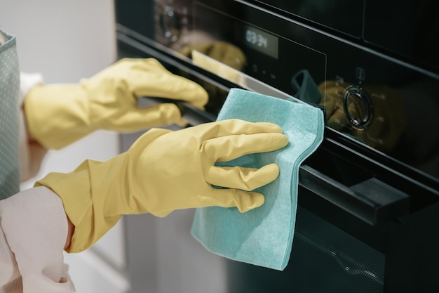 Kitchen work. Young dark-haired woman cleaning kitchen appliances