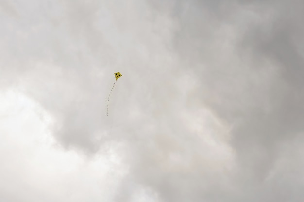 Kite flying in the beautiful autumn windy day. Blue sky background with sun and clouds.