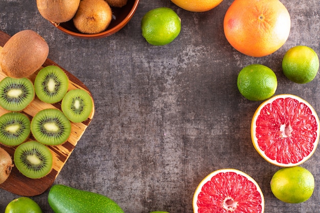 Kiwi fruit grapefruit avocado and orange fruits top view with copy space on black surface