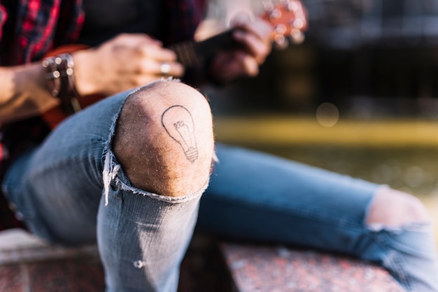 Free photo knee of boy playing the ukelele