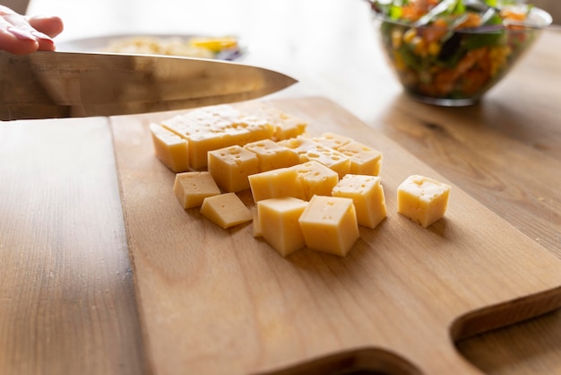 Knife cutting cheese on wooden board