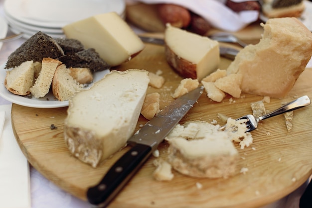 Knife and fork lie on wooden plate with different kinds of chees