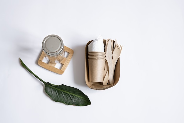 Free photo knives, forks, dishes, glass jar, paper containers for food and a natural leaves. the concept of zero waste and plastic free.