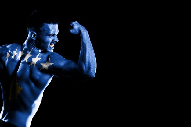 Kosovo flag on handsome young muscular man black background