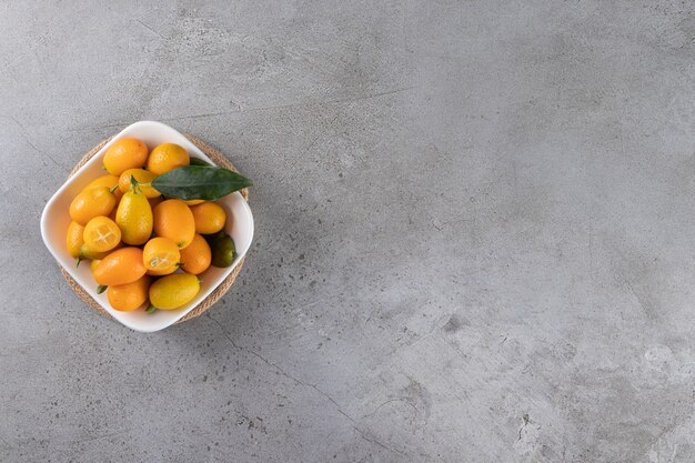 Kumquat fruits in a bowl, on the marble table.