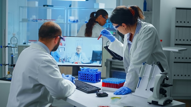 Free photo lab technicians talking on video call with professional chemist doctor explaning vaccine reactions