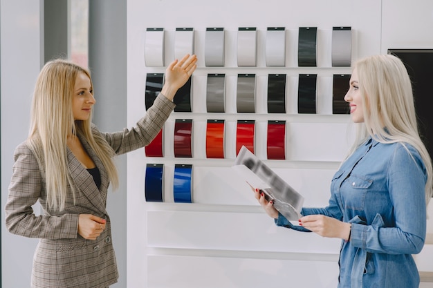 Free Photo ladies in a car salon. woman buying the car. elegant woman in a blue dress. manager helps the client.