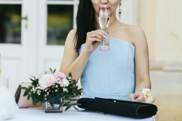 Free photo lady in blue dress drinks cold champagne