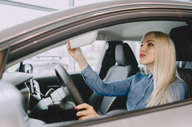 Lady in a car salon. Woman buying the car. Elegant woman in a blue dress.