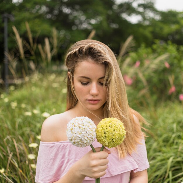 Free photo lady holding bright flowers in park