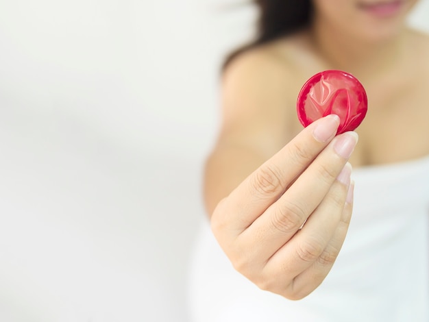 Lady is giving red condom, safe sex and contraception concept.