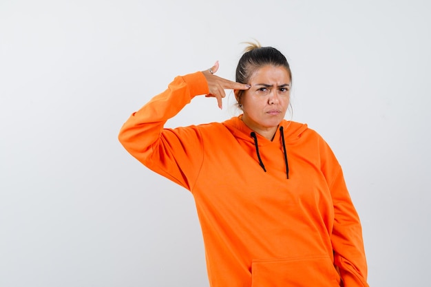 Lady making suicide gesture in orange hoodie and looking serious