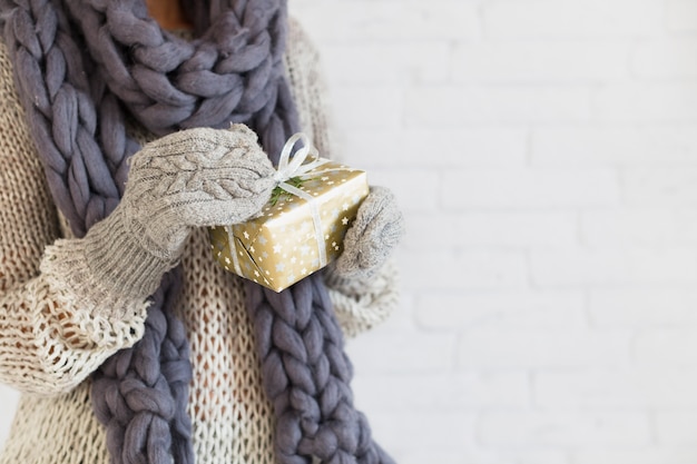 Free Photo lady in mitts and scarf with gift box in hands