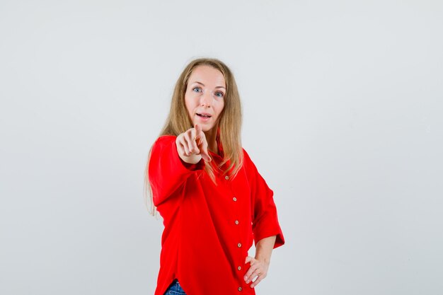 Lady pointing at camera in red shirt and looking amazed ,