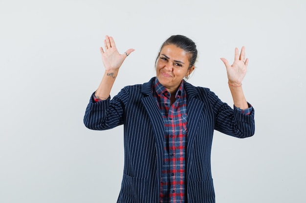 Free Photo lady raising hands in surrender gesture in shirt, jacket and looking confident , front view.