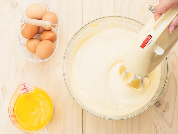 Free Photo lady's hand preparing cake using hand mixing machine with egg and butter