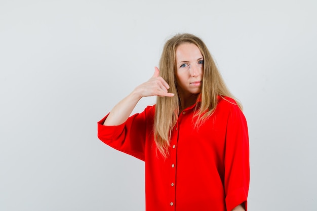 Lady showing phone gesture in red shirt and looking confident ,