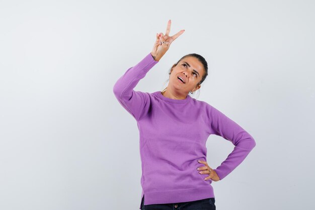 Lady showing V-sign in wool blouse and looking hopeful